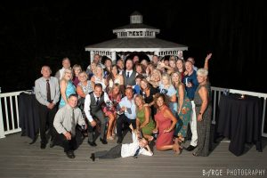 Wedding guests posing on the deck in front of the gazebo at night