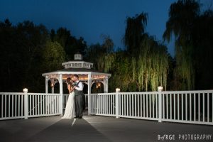 Bride and groom dancing at night in front of the illuminated gazebo