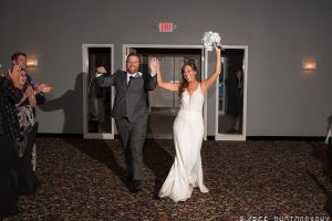 Newlyweds entering the reception hall as guests applaud