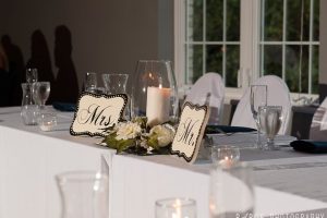 Wedding head table with candles, florals, and Mr. and Mrs. signs