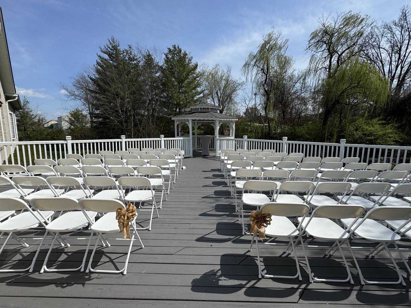 Outdoor deck with rows of white folding chairs facing the gazebo