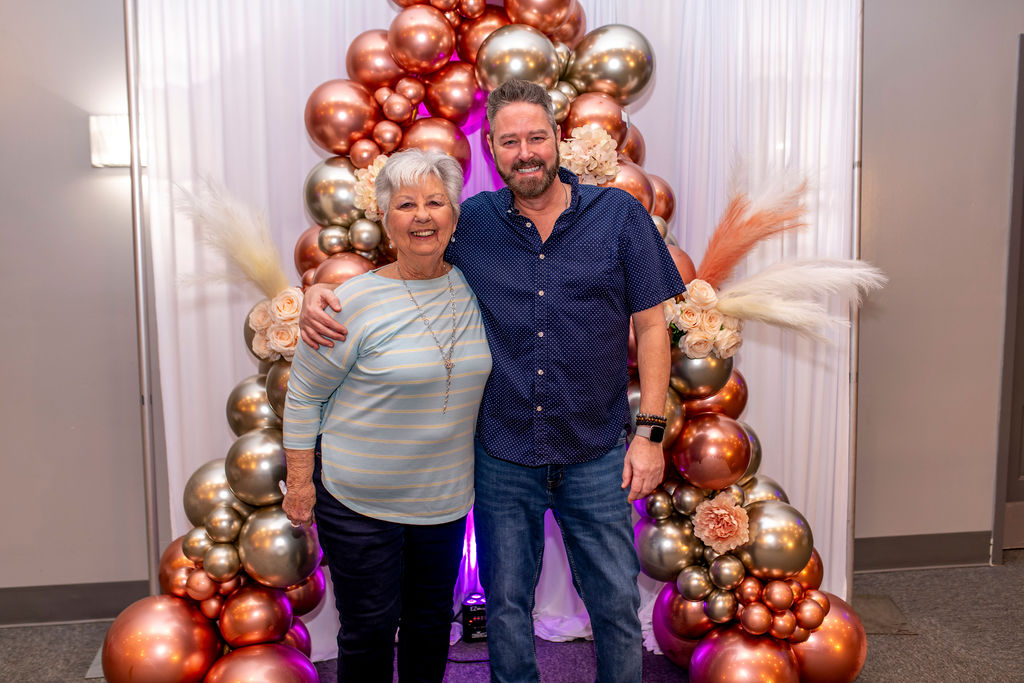 Guests posing in front of a rose gold balloon arch