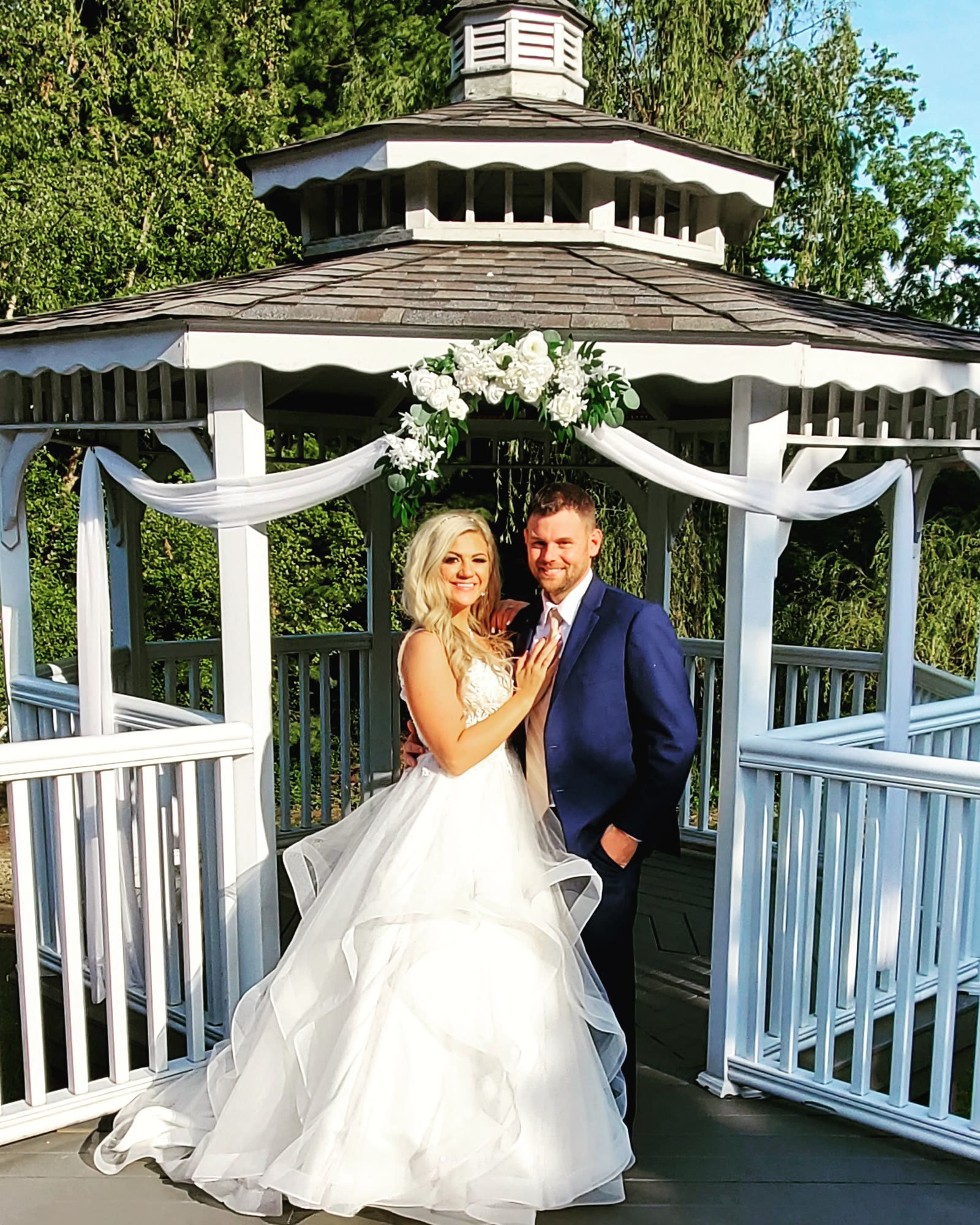 Bride and groom posing in front of the white gazebo