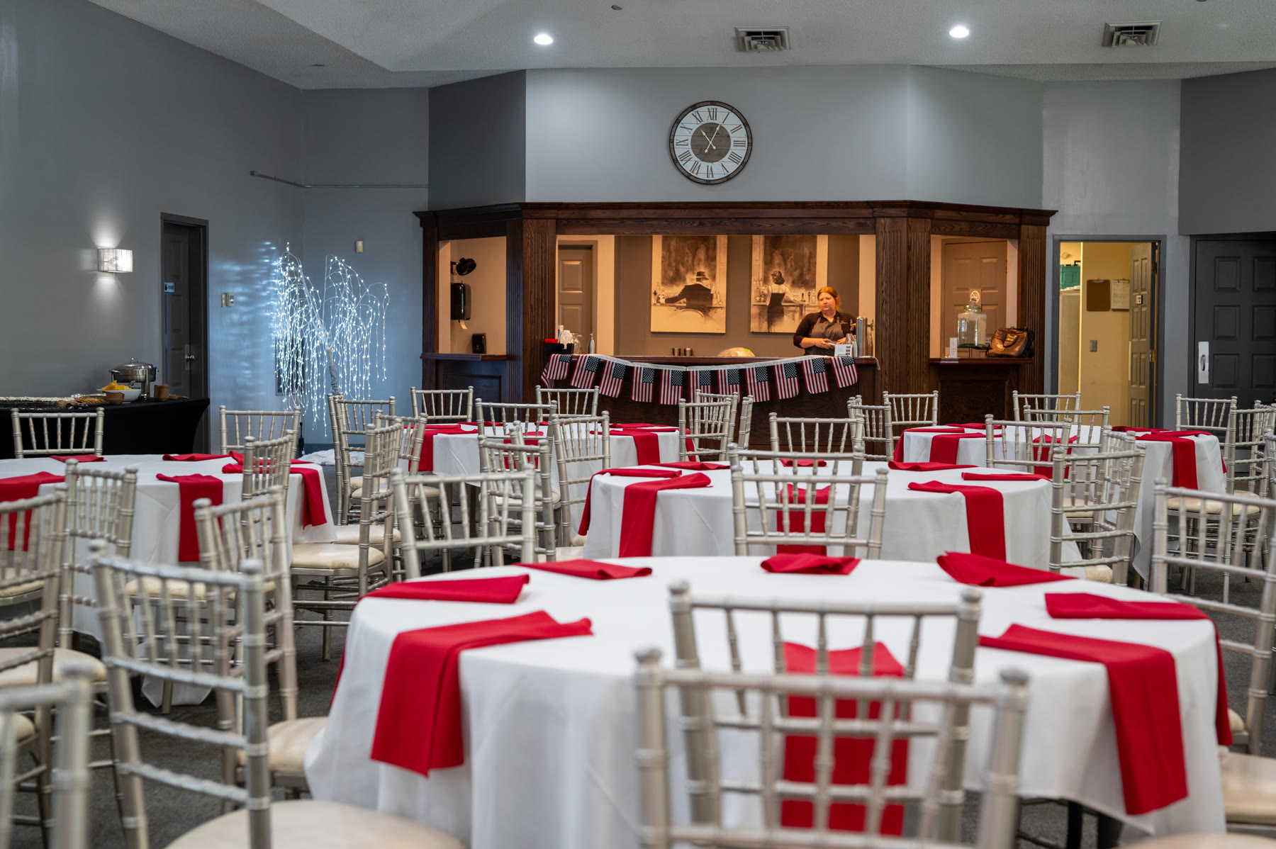Wedding reception tables dressed with white linens and red accents
