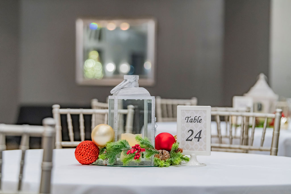 A decorated event table with a lantern and holiday greenery at Willow Event Center